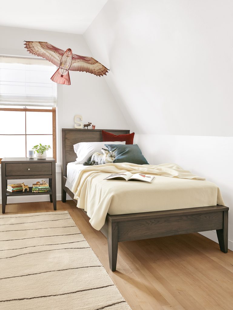 A Calvin bed and nightstand in bark looks at home with warm, creamy colors and pops of red.