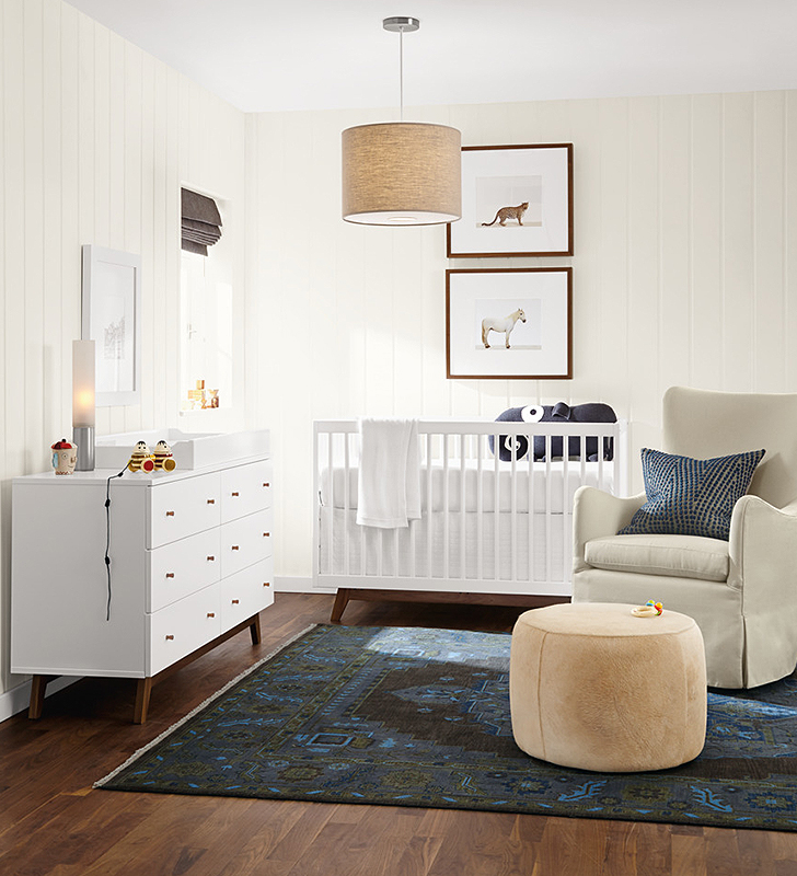 Kids furniture in nursery with crib, dresser and glider.