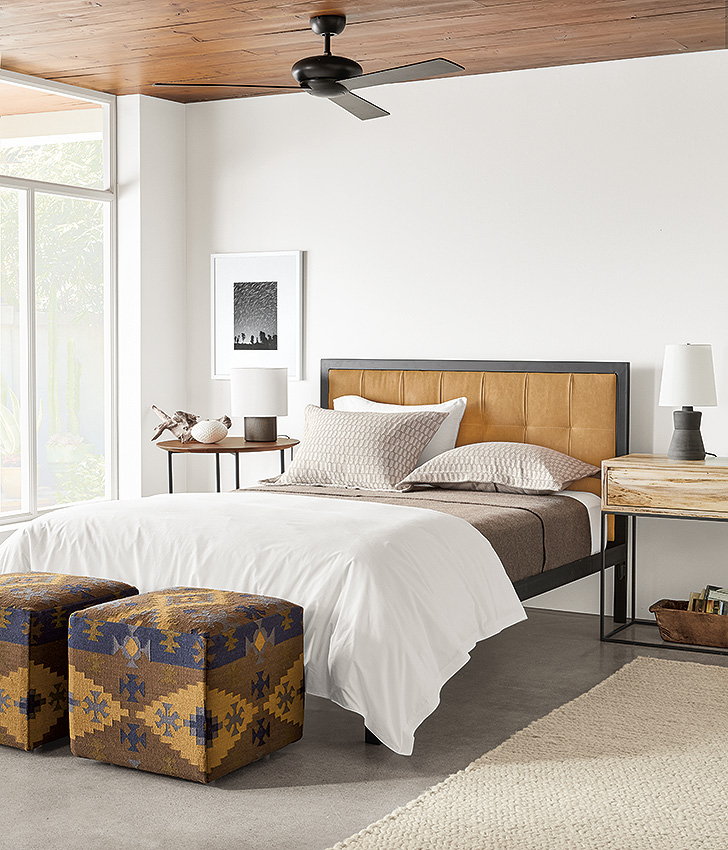 Chapman leather headboard in modern bedroom with kilim pattern ottomans