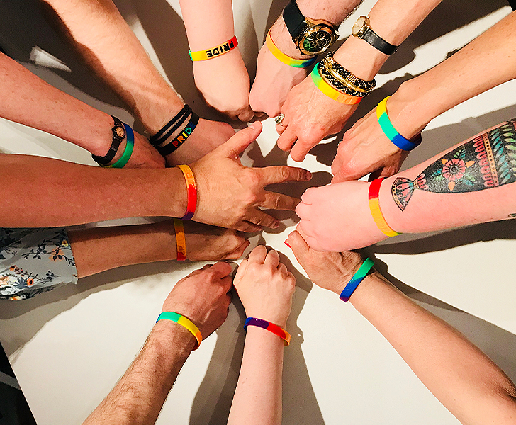 Hands in a circle with pride wristbands