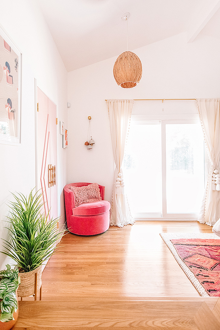 Pink velvet swivel chair in corner of master bedroom