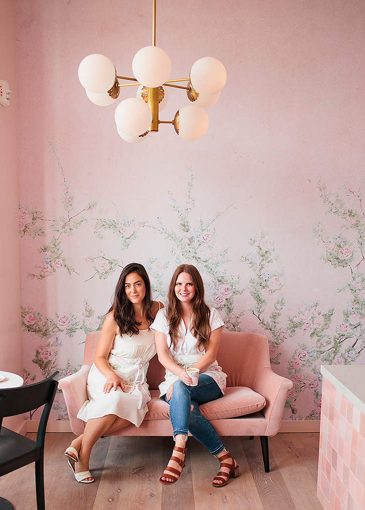 Laurel Gallucci and Claire Thomas sitting on pink velvet sofa inside Sweet Laurel Bakery