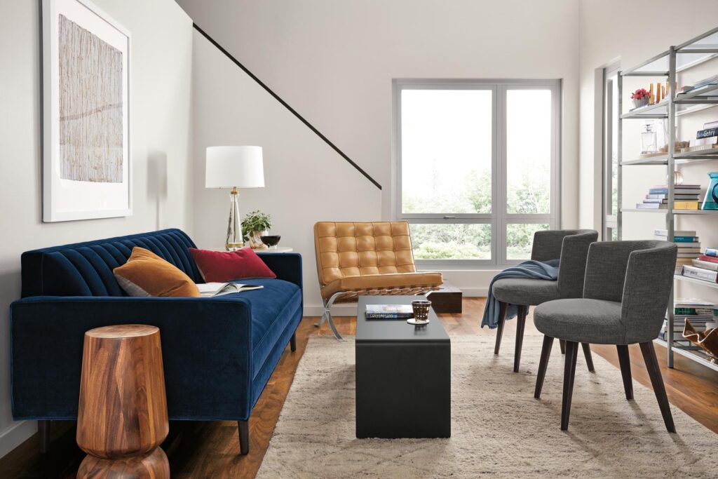 blue sofa in living room with three accent chairs.