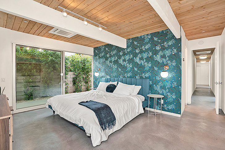 Colorful modern bedroom with patterned wallpaper and blue headboard