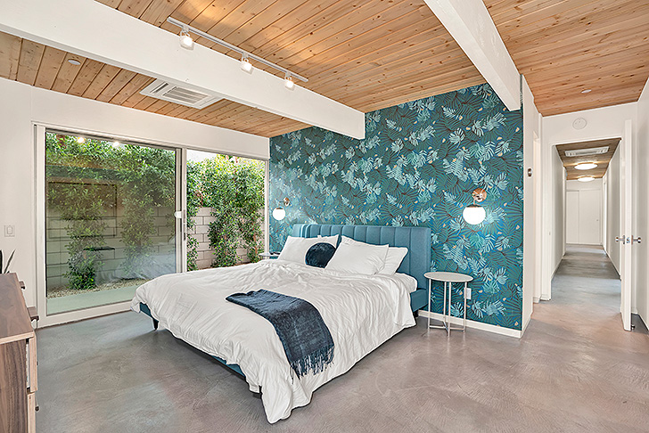 Colorful modern bedroom with patterned wallpaper and blue headboard