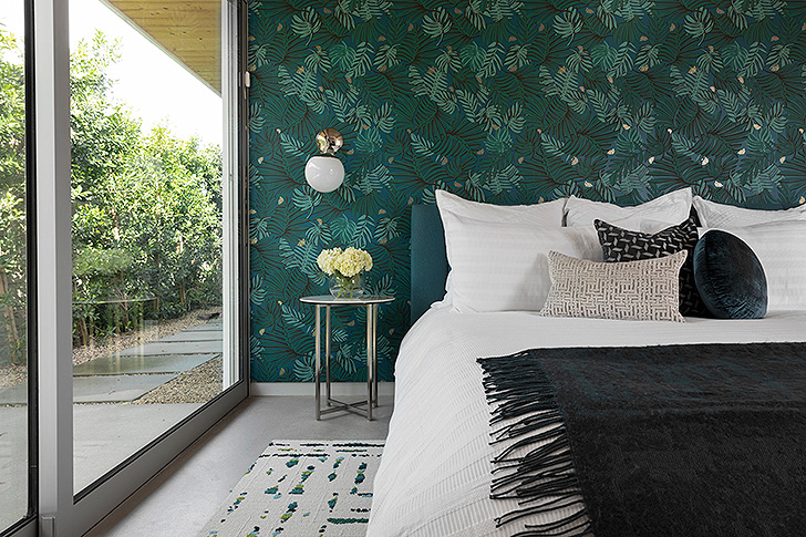 Modern bedroom with blue upholstered bed against blue patterned wallpaper