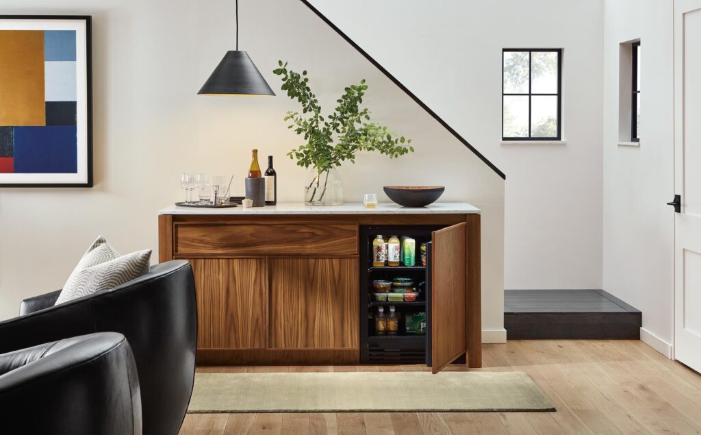 Room setting of the Amherst 72w Storage Cabinet in Walnut with Wood Refrigerator Door open.