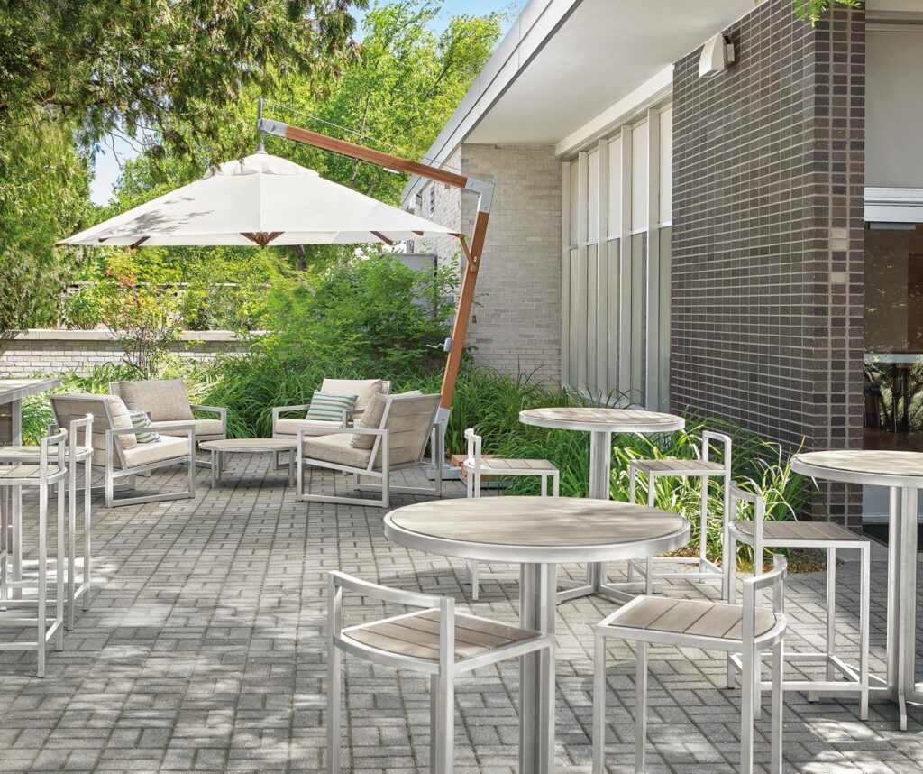 outdoor dining area with cumulo patio umbrella, montego chairs, tables, stools and bar in aged ash.