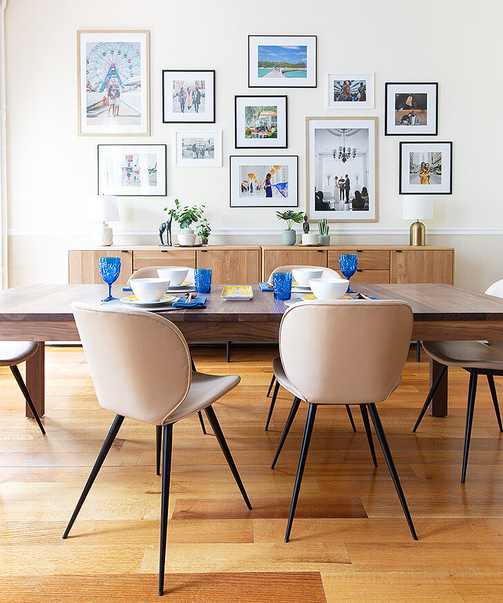 upholstered dining chairs at long wood dining table with frame wall and console cabinets in background