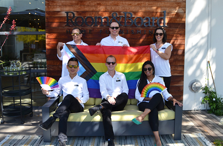 Six San Diego staff members hold a Pride flag in front of the store.