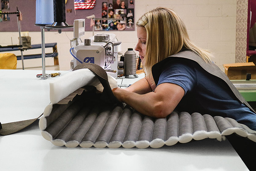 Craftsperson sewing channeling at an upholstery manufacturing facility