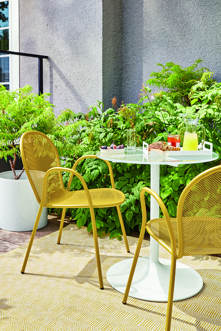 Bistro set with white table and two yellow chairs.