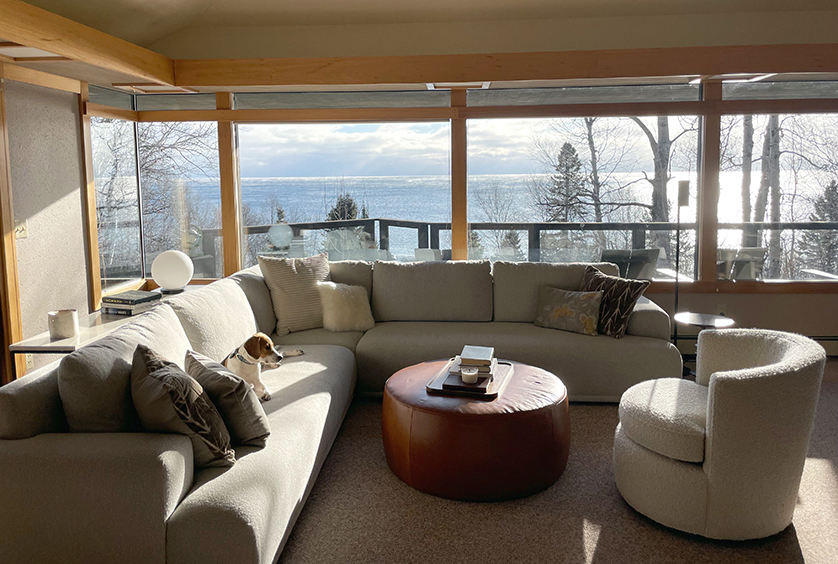 Living room furniture in sunlit cabin looking over Lake Superior