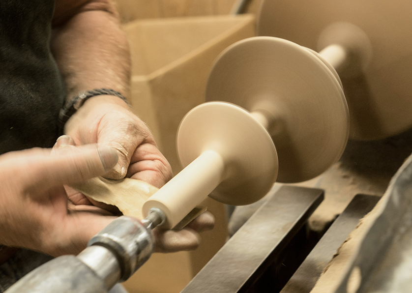 Wood on lathe with hands shaping it.